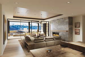 Living room with a tiled fireplace, a chandelier, a tray ceiling, a wall of windows, and a mountain view