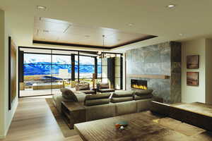 Living area featuring a fireplace, a tray ceiling, floor to ceiling windows, a chandelier, and recessed lighting