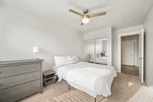 Bedroom with light carpet, ceiling fan, and a closet