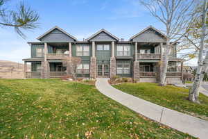 View of front of house with board and batten siding, a front yard, stone siding, and covered porch