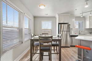 Dining space with light wood-style floors, a textured ceiling, and track lighting