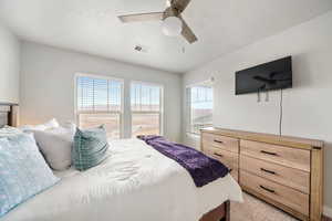 Bedroom featuring a textured ceiling, light colored carpet, and a ceiling fan