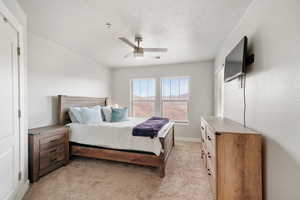 Bedroom featuring light colored carpet, a ceiling fan, and a textured ceiling