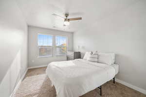 Carpeted bedroom featuring a textured ceiling and ceiling fan