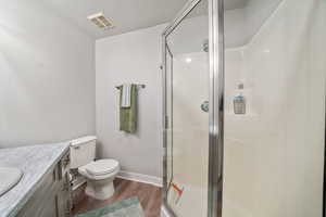 Full bathroom with vanity, dark wood-style floors, a stall shower, and a textured ceiling