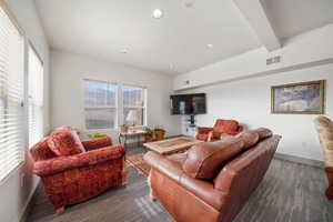 Living room with beam ceiling, recessed lighting, and dark carpet