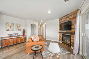 Living room featuring light wood-type flooring, a fireplace, arched walkways, and recessed lighting