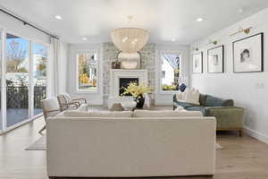 Living area with light wood-type flooring, a fireplace, recessed lighting, and a chandelier