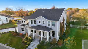 Rear view of property featuring a lawn, roof with shingles, and covered porch