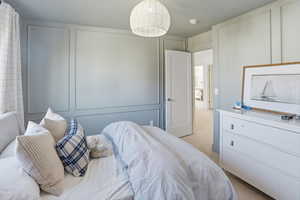 Bedroom featuring light carpet and a decorative wall