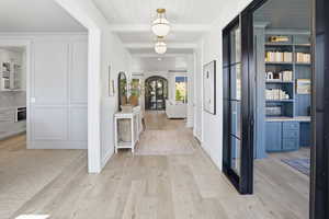 Entrance foyer featuring light wood-type flooring, a wooden ceiling with exposed beams, and french doors