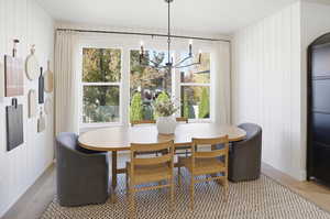 Dining area featuring wood walls, light wood-style flooring, and a chandelier
