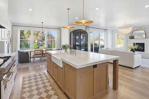 Kitchen featuring light wood finished floors, hanging light fixtures, recessed lighting, gas range, and light stone counters