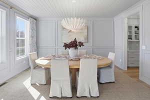 Dining room with a decorative wall, a chandelier, wooden ceiling, and wood finished floors