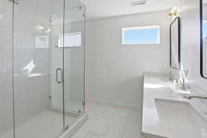 Bathroom with a stall shower, double vanity, and light marble finish floors