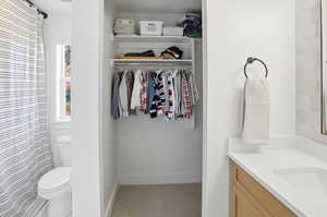 Bathroom with vanity, a shower with shower curtain, and a walk in closet