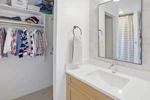 Bathroom with vanity, a walk in closet, and light carpet