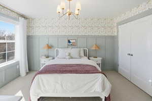Bedroom featuring a decorative wall, wallpapered walls, a wainscoted wall, carpet flooring, and a chandelier