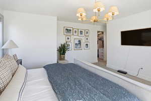 Carpeted bedroom featuring a chandelier and a walk in closet