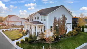 Rear view of house featuring a lawn, roof with shingles, and covered porch