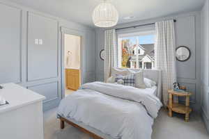 Bedroom featuring a decorative wall, light colored carpet, and ensuite bathroom