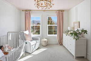 Bedroom with light carpet, a nursery area, a chandelier, and a mountain view
