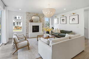Living room featuring healthy amount of natural light, light wood finished floors, a fireplace, a chandelier, and recessed lighting