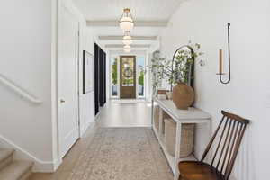 Foyer featuring stairway, light wood-style floors, and a wooden ceiling with exposed beams