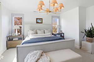 Carpeted bedroom featuring a chandelier and baseboards