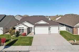 View of front of house featuring a front lawn, a residential view, driveway, and an attached garage