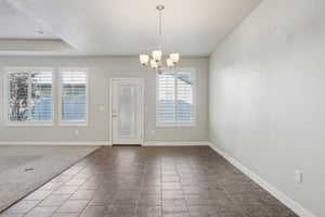 Unfurnished dining area featuring a chandelier and carpet floors