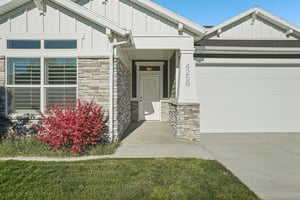 View of front facade featuring stone siding, board and batten siding, concrete driveway, and an attached garage
