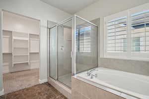 Full bath featuring a walk in closet, a stall shower, and a garden tub
