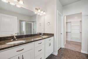 Bathroom featuring a walk in closet, double vanity, and a stall shower