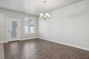 Unfurnished room featuring baseboards and a chandelier