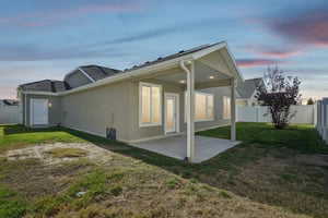 Back of house at dusk with a patio area and a fenced backyard