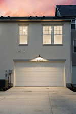 View of side of home featuring an attached garage, stucco siding, and concrete driveway
