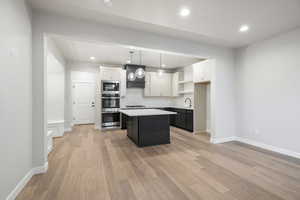 Kitchen featuring white cabinets, recessed lighting, pendant lighting, backsplash, and light wood-style floors