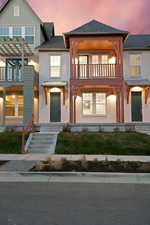 View of front of home featuring stucco siding, a balcony, and a shingled roof