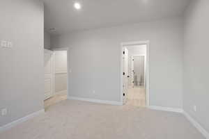 Unfurnished bedroom featuring light carpet, ensuite bath, and recessed lighting