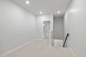 Corridor with an upstairs landing, light carpet, and recessed lighting