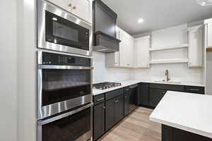Kitchen with decorative backsplash, open shelves, stainless steel appliances, white cabinets, and recessed lighting