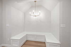 Mudroom featuring a chandelier, light wood-style flooring, and vaulted ceiling
