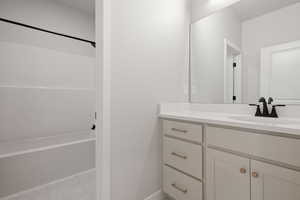 Bathroom with light marble finish floors, vanity, and  shower combination