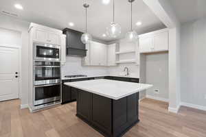 Kitchen featuring backsplash, dark cabinetry, white cabinetry, hanging light fixtures, and recessed lighting