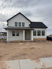 View of front of home featuring a shingled roof, board and batten siding, and covered porch