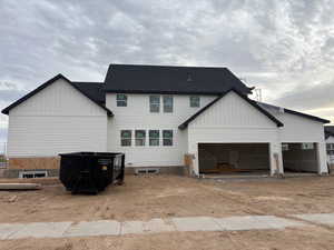 Back of property featuring board and batten siding, driveway, a garage, and roof with shingles