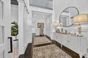 Entryway with a decorative wall, dark wood-style flooring, and a wainscoted wall