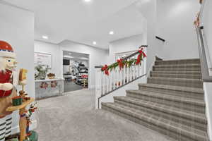 Stairs with carpet floors and recessed lighting