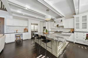 Kitchen featuring a kitchen bar, tasteful backsplash, a spacious island, dark stone countertops, and decorative light fixtures